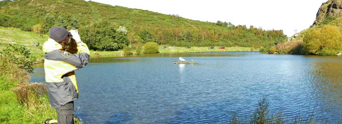 Countryside ranger Luke looking at loch with binoculars