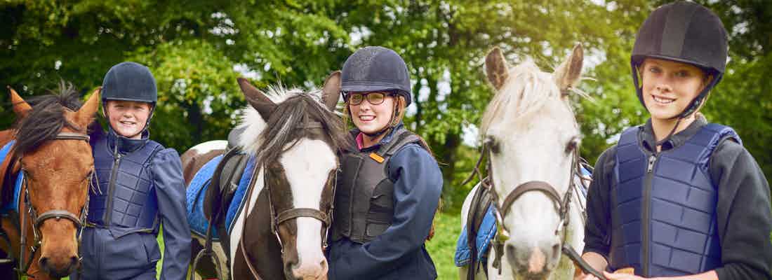 three young horse riders wearing protective gear