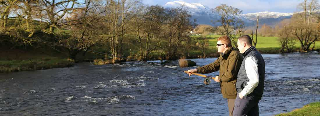 Fisherman by Scottish river with guide