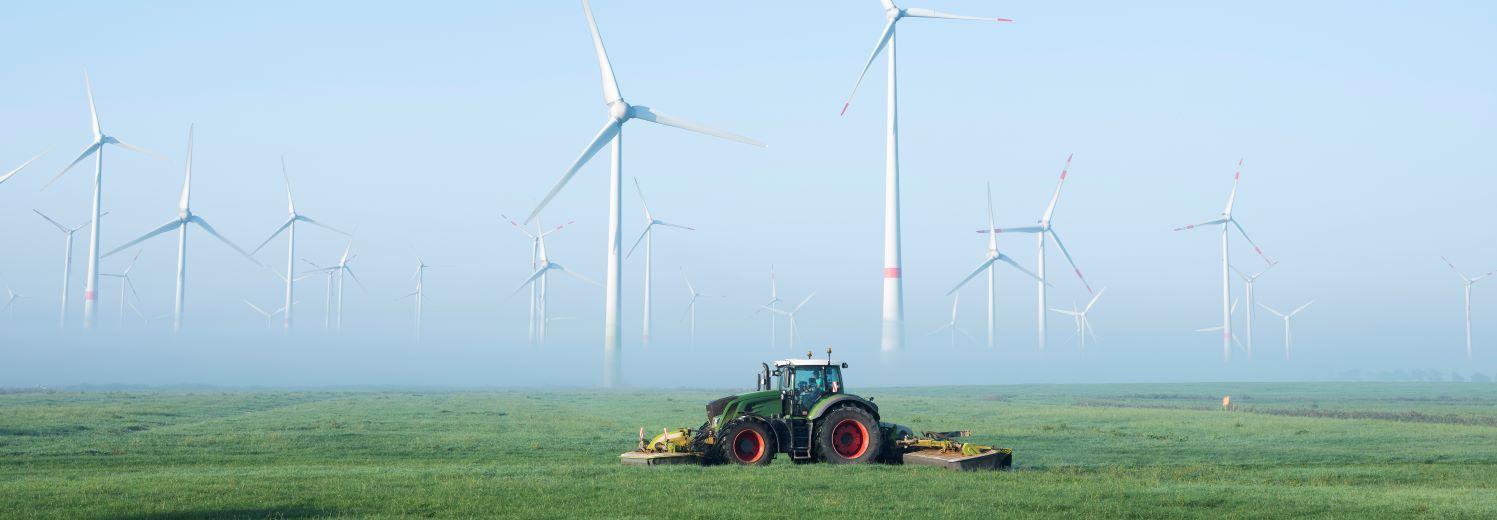 Tractor cutting grass in front of wind farm