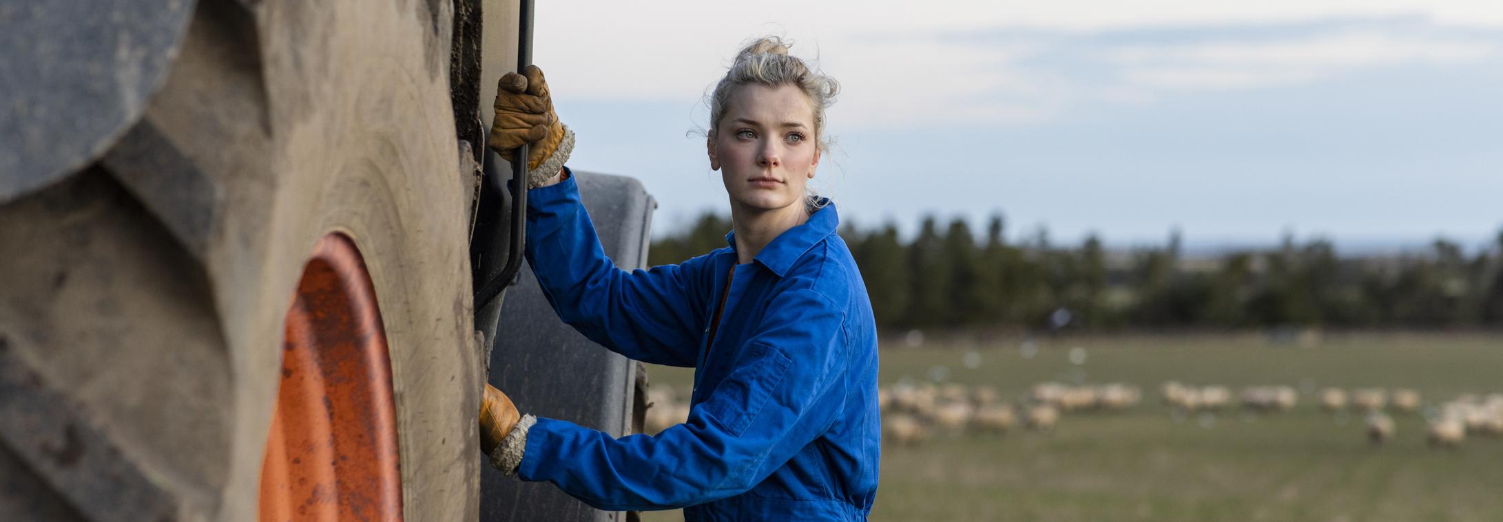 Young woman standing next tractor