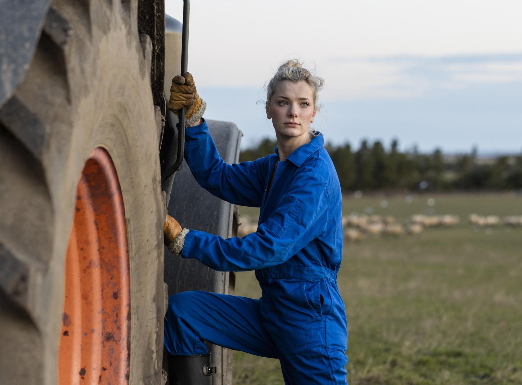 Young woman standing next tractor