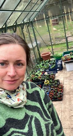 Woman inside greenhouse looking at camera