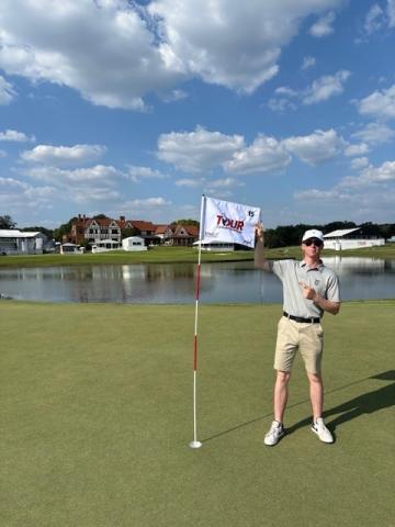 Man in shorts on golf green holding flag