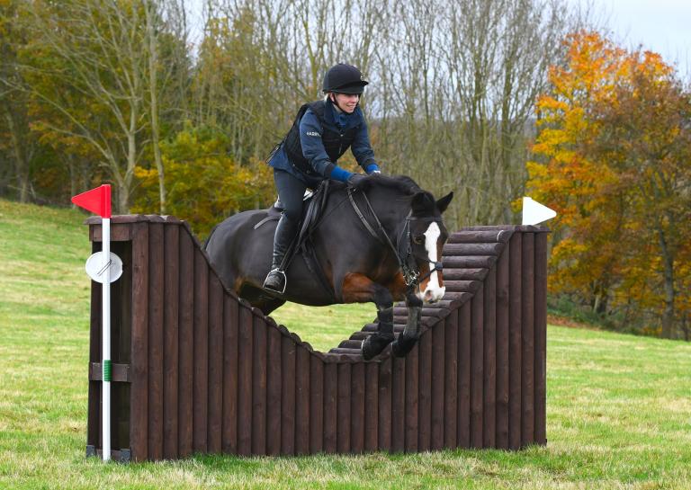 Woman riding horse going over jump